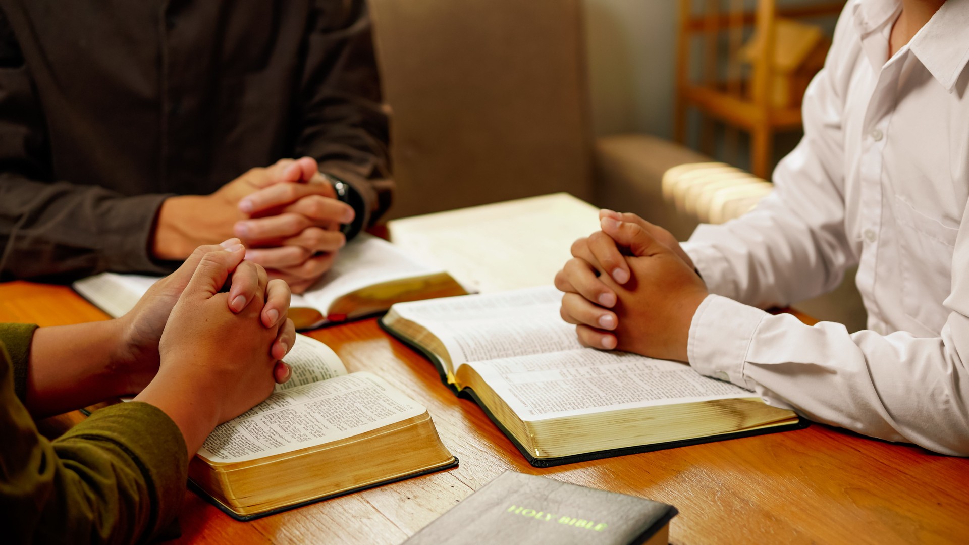 Christian Bible Study Concepts. Christian group or family prayer together with a holy bible on a wooden table in church for worship to god in the morning. people pray with faith, Spirituality.